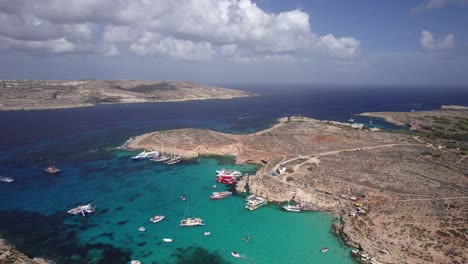 Drone-Descends-Quickly-Into-Blue-Lagoon,-Comino-Island,-Malta