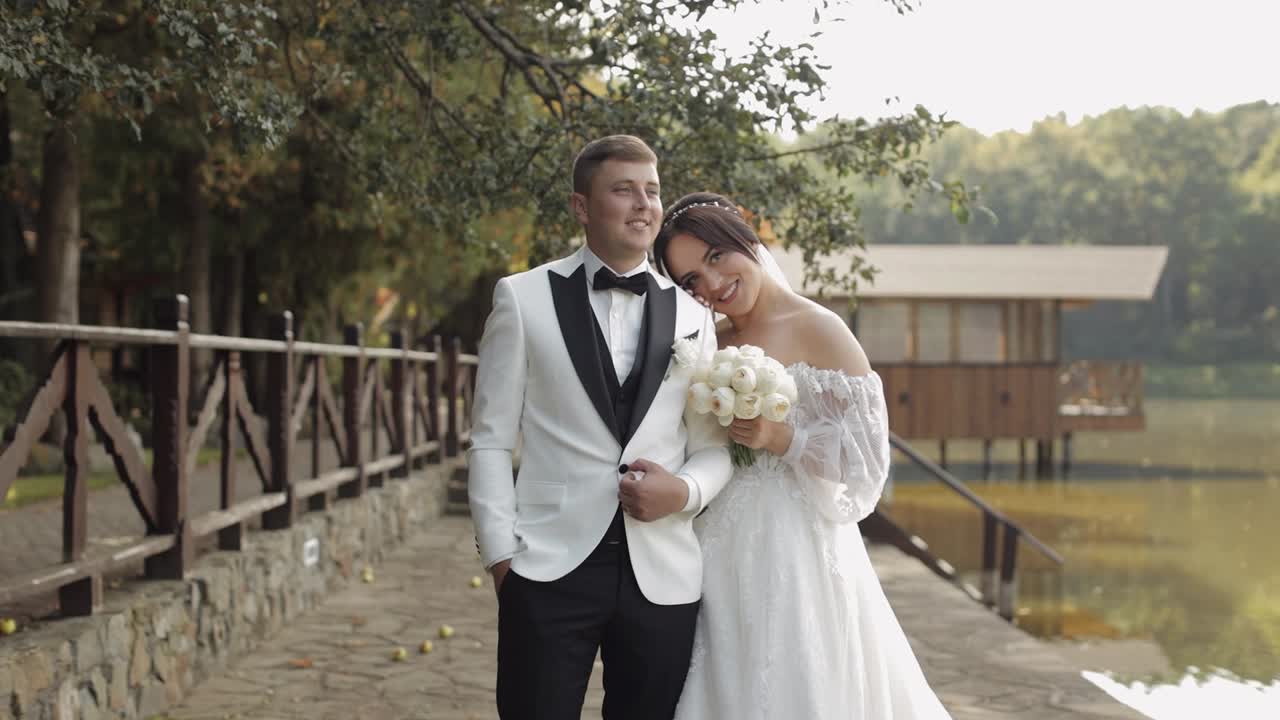 Gli sposi posano per una foto di matrimonio davanti a un lago.