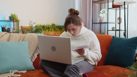 Stressed-young-woman-looking-at-unpaid-bank-debt-loan,-doing-paperwork,-planning-budget-throws-bills