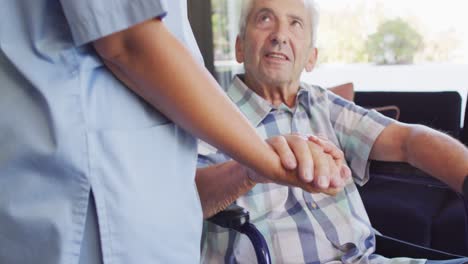 video of midsection of biracial female doctor taking care of caucasian senior man