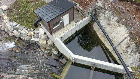 Small-intake-reservoir-for-a-10-gwh-hydroelectric-powerplant-named-Markaani-in-vaksdal-Norway---Aerial-flying-close-over-intake-with-valve-control-house