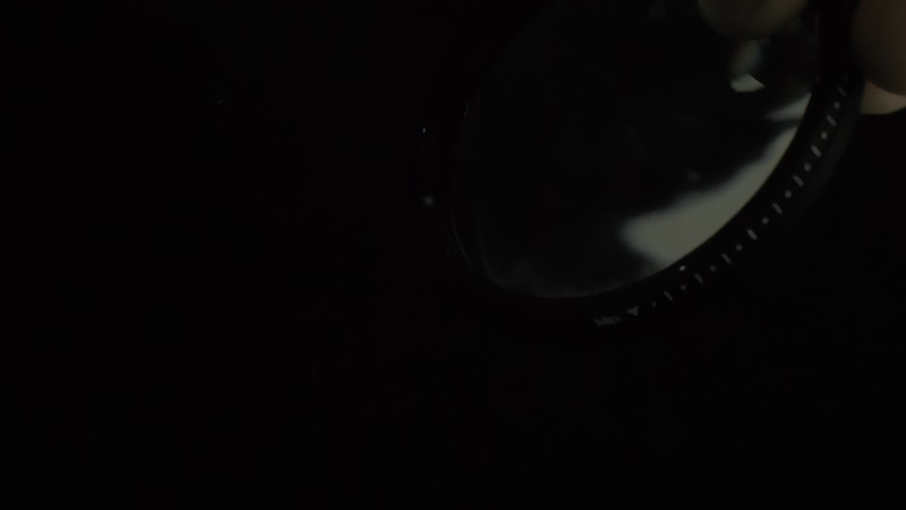 primer plano de la lente negra y el filtro sosteniendo en la mano, efecto de fondo negro