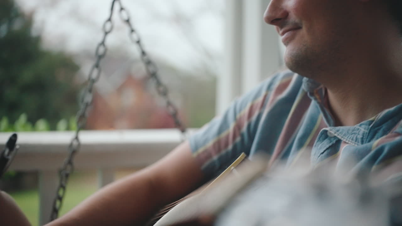 Man Playing Guitar and Writing on Porch