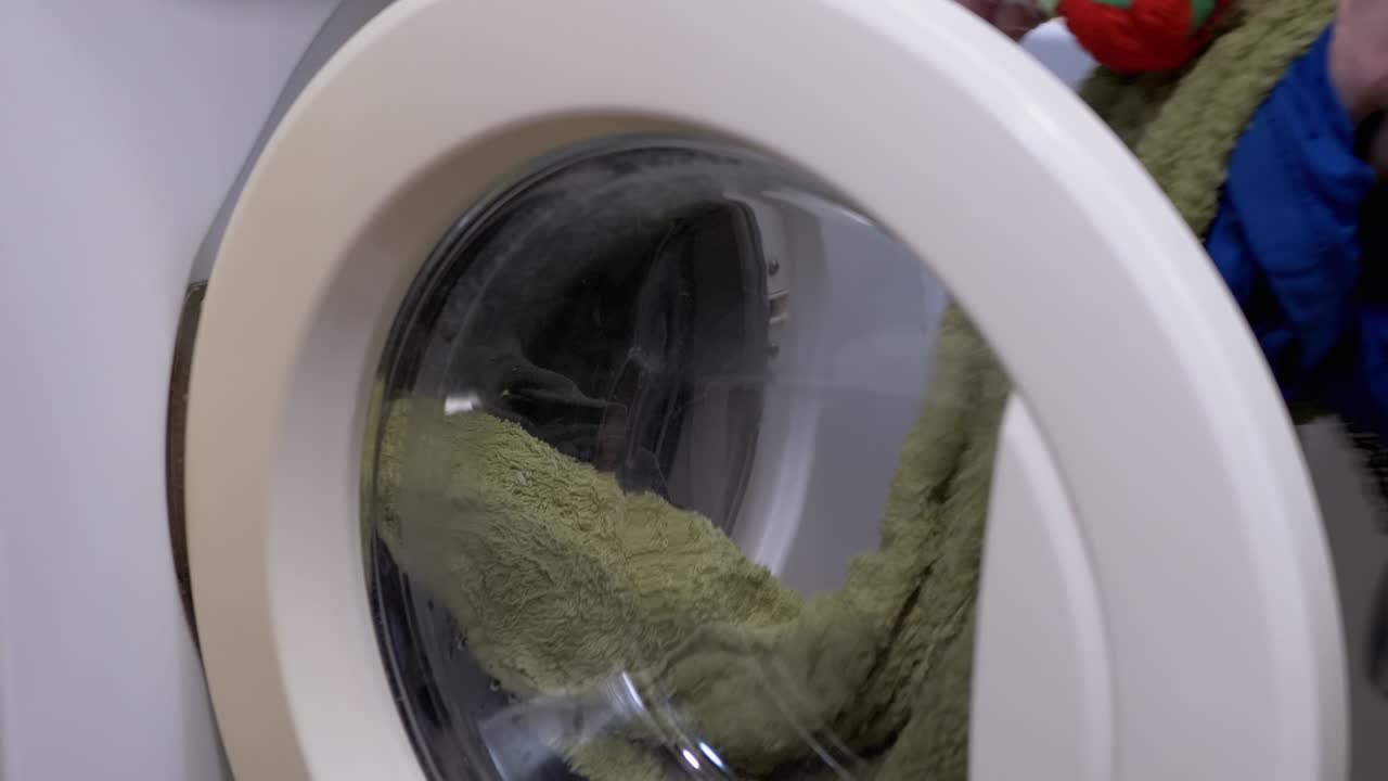 여성 손은 세탁기에서 깨하고 은 색의 세탁기를 얻습니다.