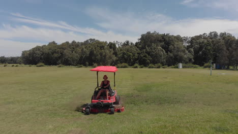 chica rubia cortando hierba en el campo con cortacésped