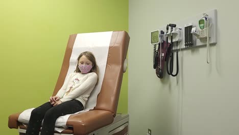 :Portrait-of-child-sitting-on-chair-in-waiting-area-at-facility