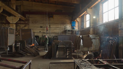 Worker-pulls-goat-crane-hook-walking-along-plant-workshop