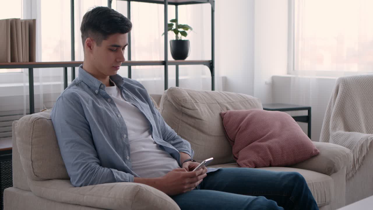 소파에서 스마트폰을 사용하는 젊은 남자