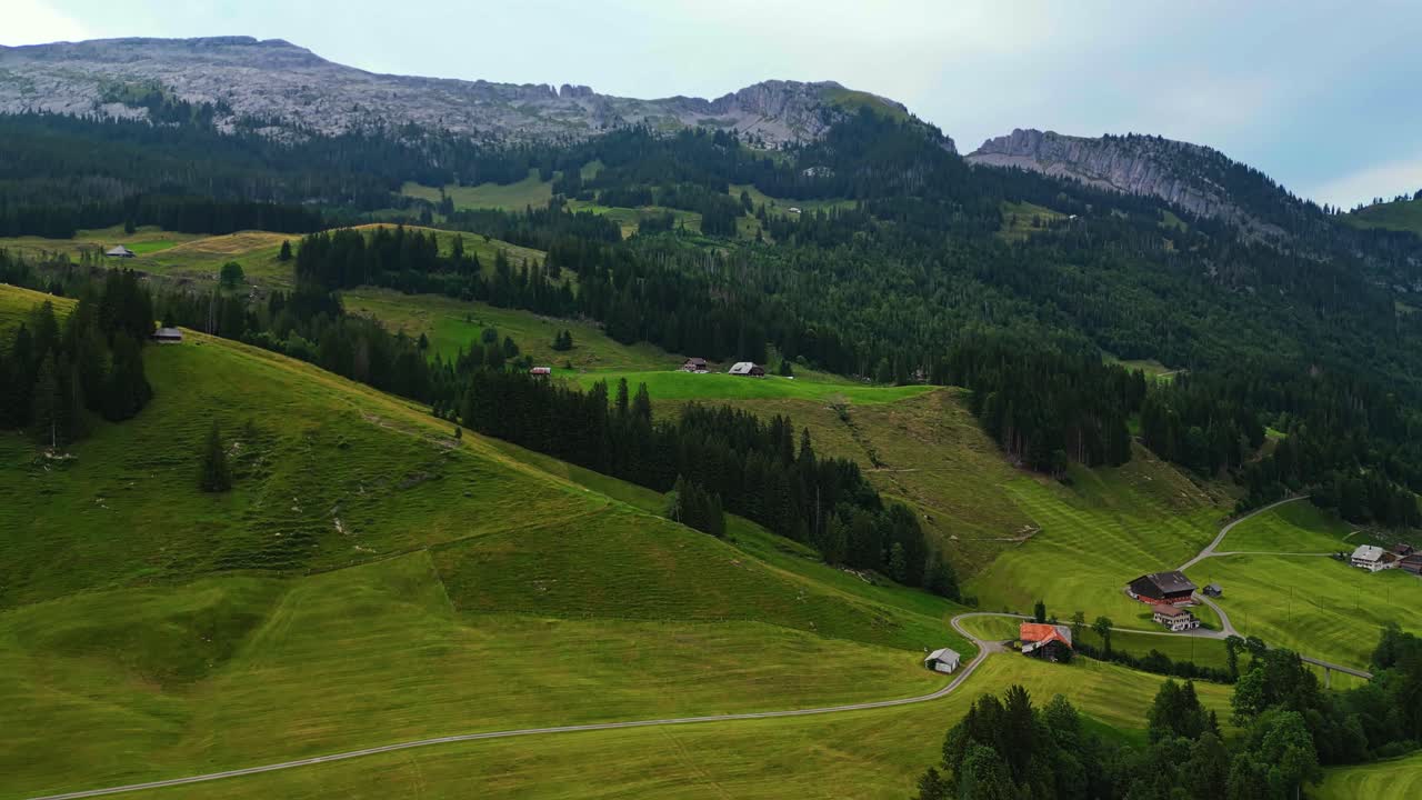 vista aérea de un pintoresco pueblo en los alpes suizos, colinas verdes, pinos, rodeado de montañas en el fondo