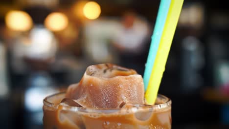 refreshing iced coffee beverage with colorful straw and ice cubes in a cozy café setting, perfect for a warm day delight