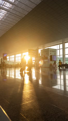 passengers walking in airport terminal with afternoon sunlight in vertical