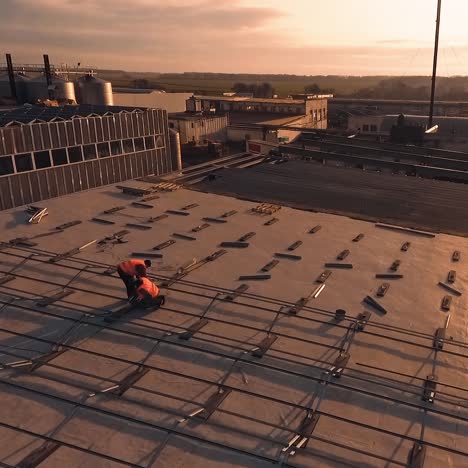construction of solar farm on roof of a building. workers install metal constructions for solar panels at sunset. aerial view.