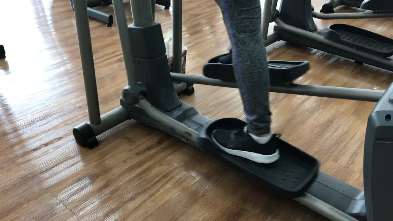 Primo piano di un piede che si allena sulla macchina stepper in palestra, macchina stepper sul pavimento in legno