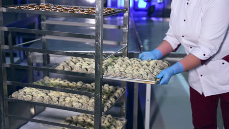 Confectionery employee puts a tray full of candies into a special shelves. Handmade manufacturing of sweets at the food factory.