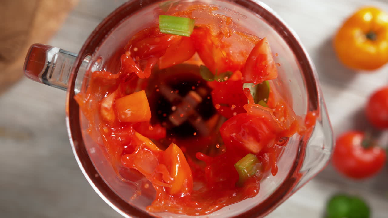 batido de tomate para perder peso con apio mezclado en una licuadora de vidrio a cámara lenta, vista de arriba, dentro del dispositivo
