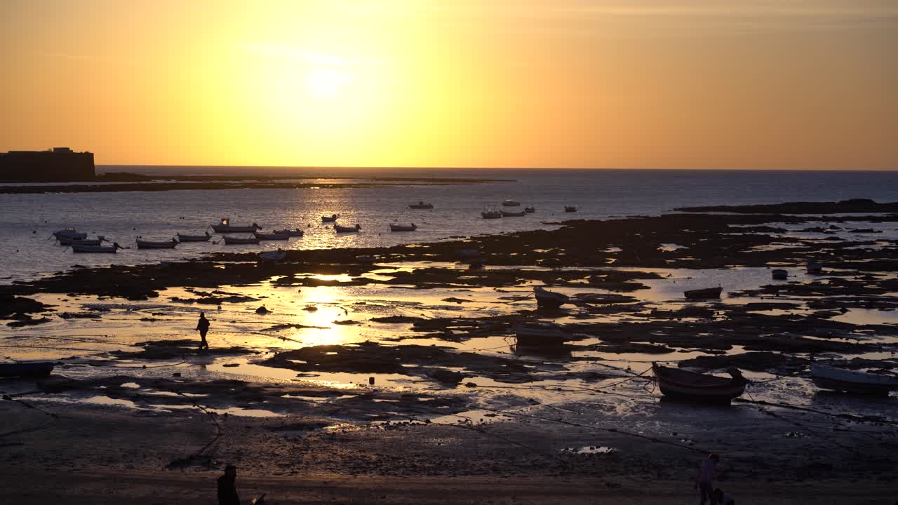 Silhuetas de pequenos barcos de pesca no oceano durante a maré baixa ao pôr do sol