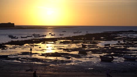 kleine fischerboot-silhouetten am meer bei ebbe bei sonnenuntergang