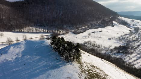 Aerial-tilting-down-from-Castle-Teck-revealing-stunning-mountain-and-kids-sledding-down-in-winter-wonderland-landscape-in-Swabia,-Germany