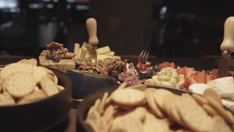 Close-up-of-cheese-and-charcuterie-platter-on-buffet-at-party,-bowls-with-crackers