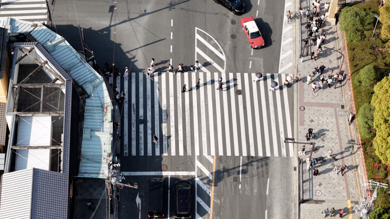 Aerial drone view of people crossing the street in the city in daylight