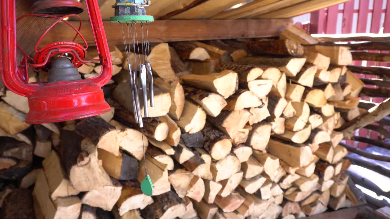 still shot of a lantern, wind chimes, and pile of chopped fire wood stacked for the winter in 4k 23.98p for b roll
