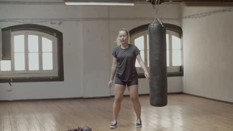 Long-shot-of-serious-female-sportsman-swinging-legs-in-gym