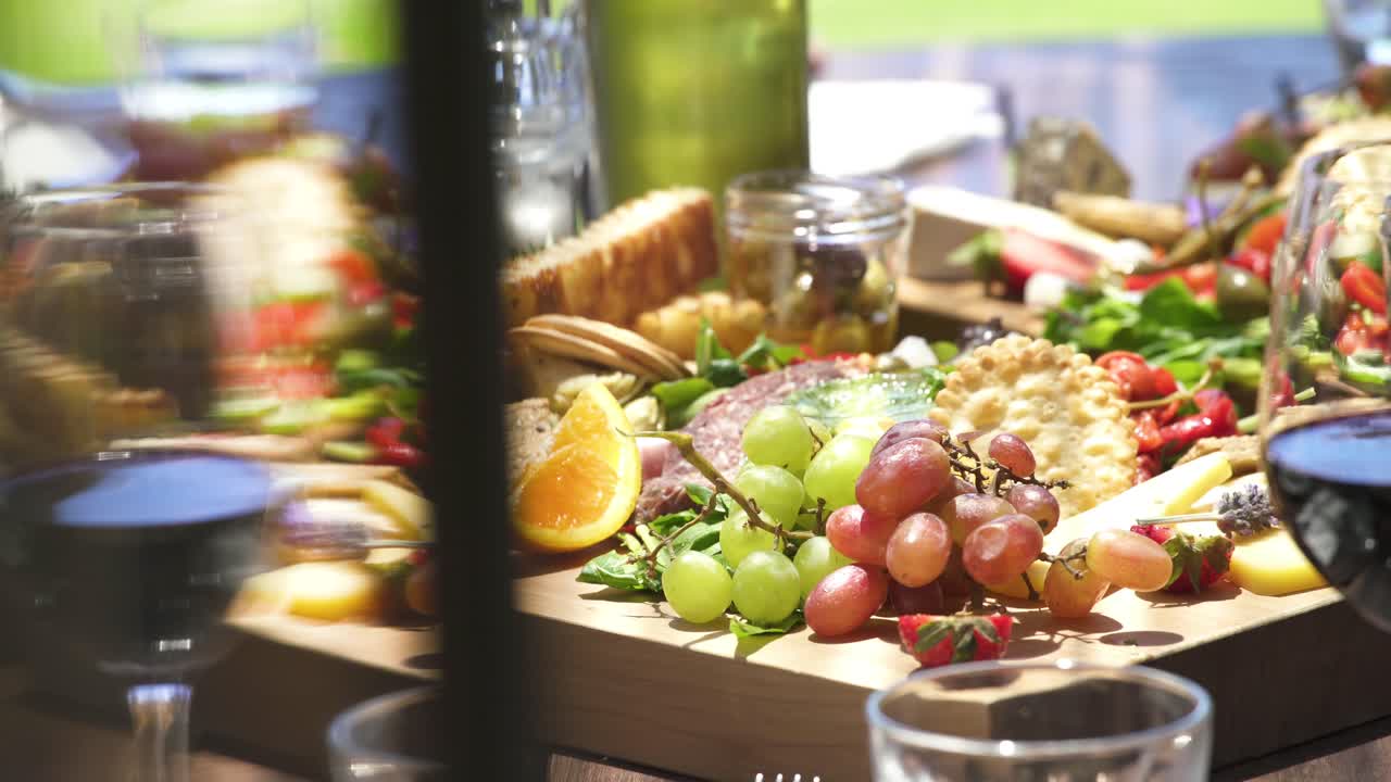 Close shot of food platter with fruits cheese wine and meat.