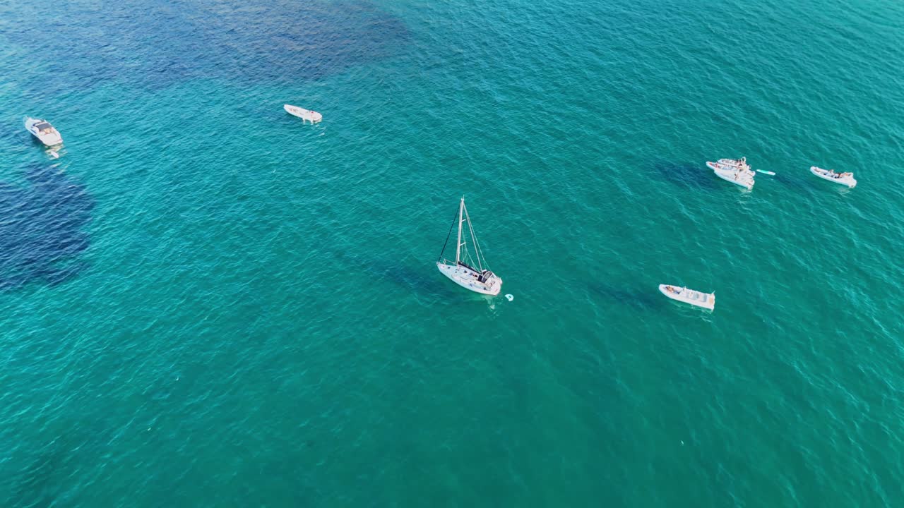 Aerial view of sailboats on clear turquoise sea, sunny day, peaceful vibe