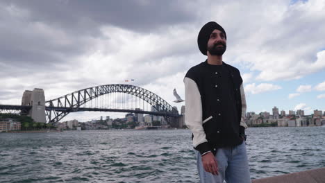 bearded punjabi sikhi man smiling near sydney harbour bridge in new south wales, australia