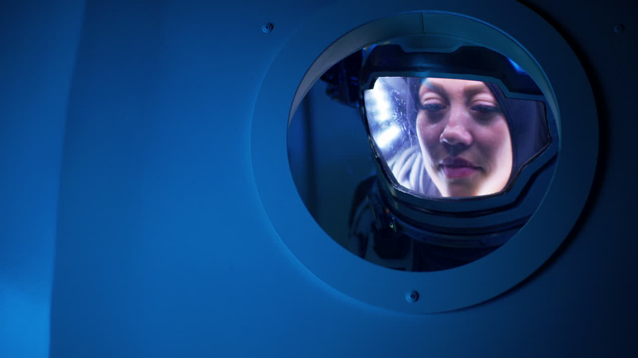 Woman in Space Suit Looking Through a Spacecraft Window