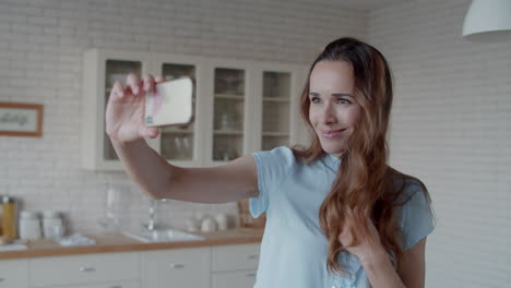 beautiful woman taking selfie photo in kitchen. woman posing for photo.