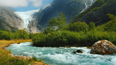 Clear-Water-In-A-Mountain-Stream-Against-The-Background-Of-A-Glacier-In-The-Mountains-Briksdal-Glaci