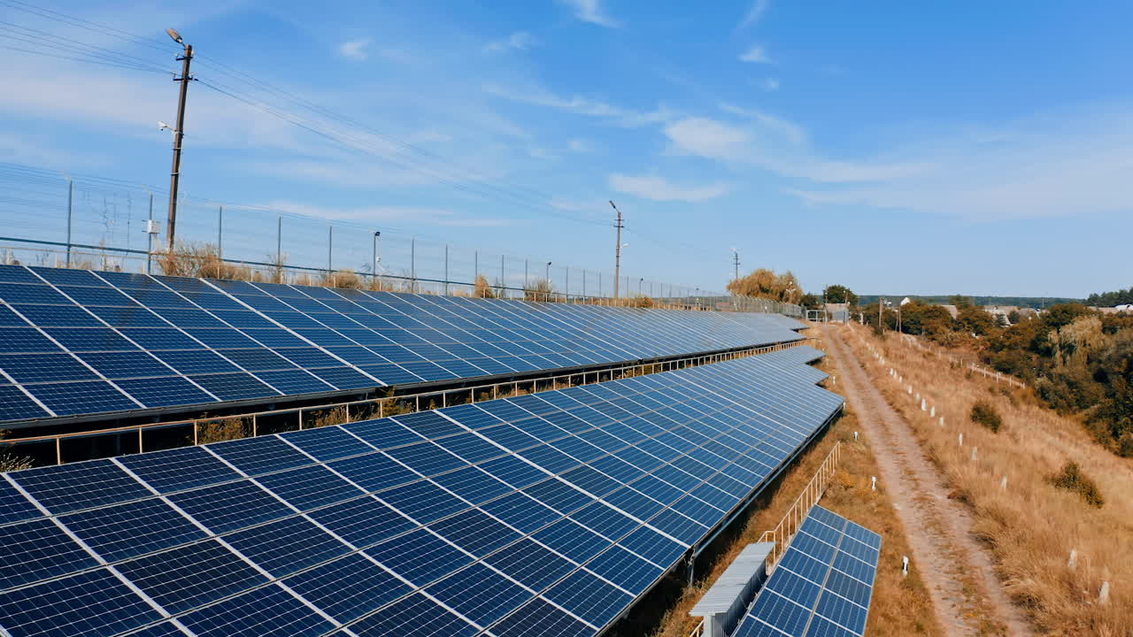 Few rows of solar panels in the countryside. Blue photovoltaic sunny batteries on the ground at sunlight. Alternative source of ecological energy.
