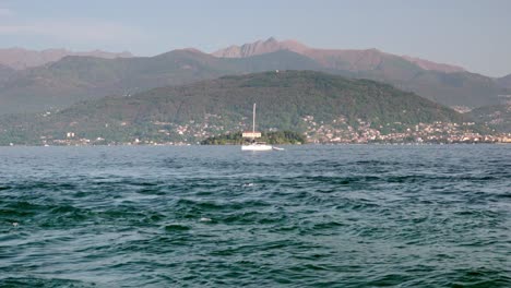 a sailing boat with retracted sails moves across lake maggiore