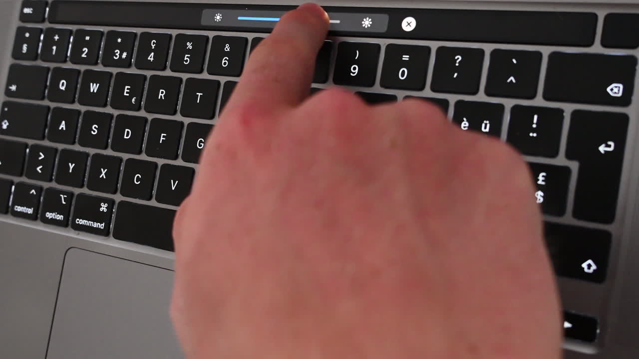 un joven está moviendo el control deslizante de brillo en su teclado, uso de computadora portátil, dispositivo electrónico