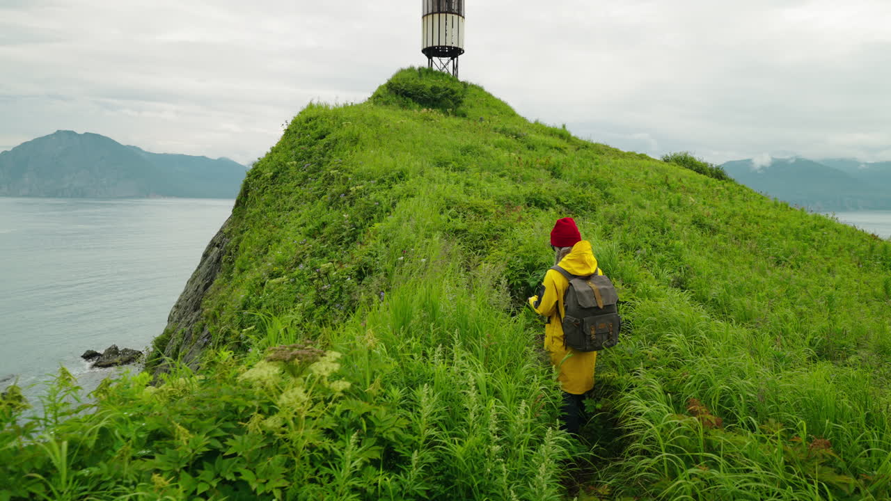 Woman Hiking on a Coastal Hilltop near a Lighthouse