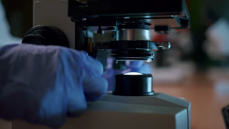 A-young-female-scientist-adjusts-the-professional-microscope-in-the-laboratory—a-close-up-shot-of-the-microscope-focusing-block