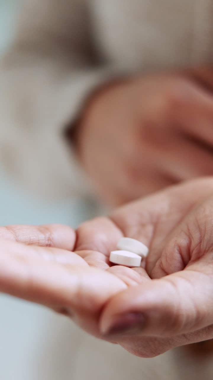 Primer plano de una persona tomando pastillas blancas de la mano