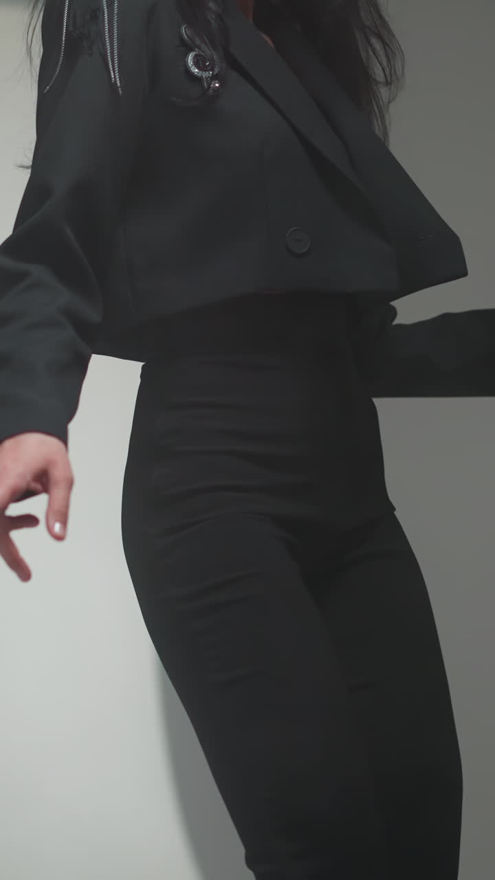 mujer sin rostro en un traje negro bailando lentamente en un escenario de estudio suavemente borroso