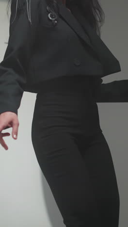faceless woman in a black suit dancing slowly in a softly blurred studio setting