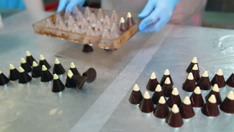 confectioner's hands extracting chocolate candies from the molds. close up. handmade sweets manufacturing at confectionery.