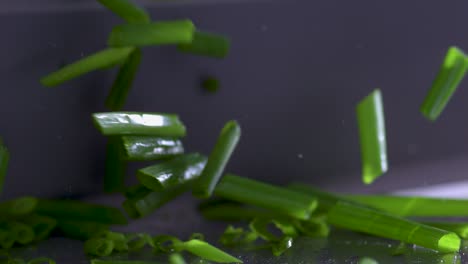 Extreme-close-up-cutting-fresh-green-chives-with-a-sharp-silver-knife,-slowmo
