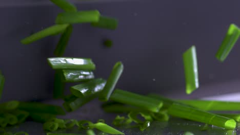 extreme close-up cutting fresh green chives with a sharp silver knife, slowmo