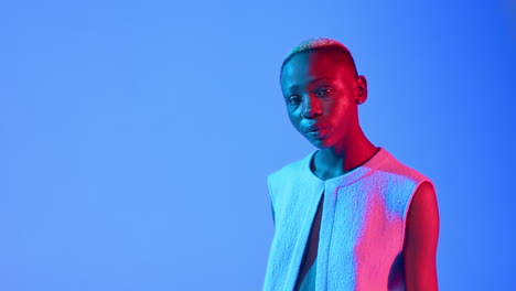 Fashion-and-beauty-concept-as-a-Black-female-model-walks-towards-camera-and-poses-on-a-blue-background-with-copy-space