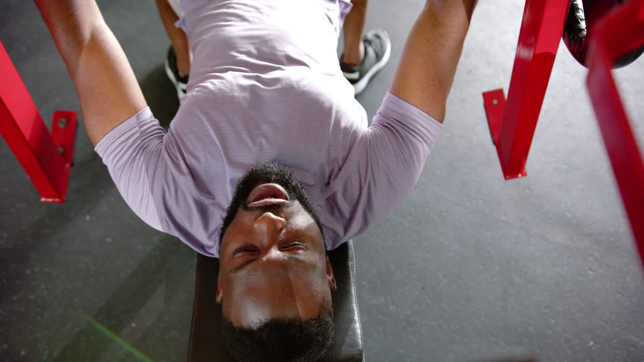 Lifting weights, african american man exercising on bench press in gym, focusing on fitness