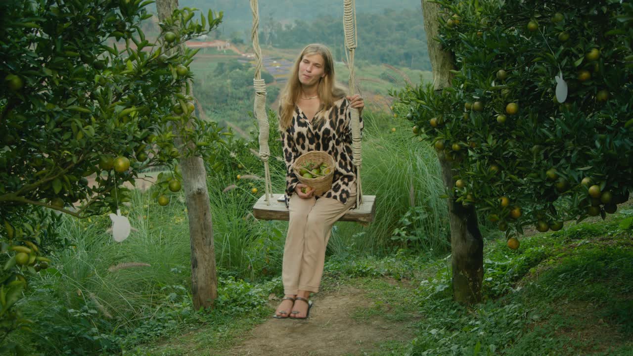 Woman relaxing on a swing in an orange orchard