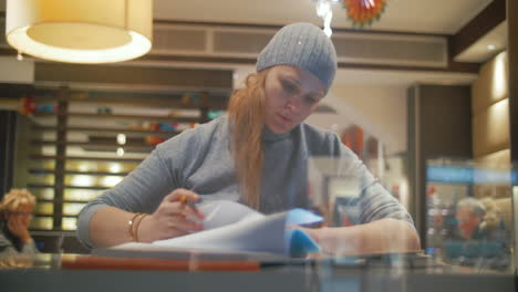 mujer en un café trabajando con un bloc de notas y tomando notas