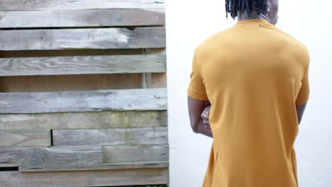 rear view of african american man in yellow t shirt, with arms crossed, slow motion, copy space