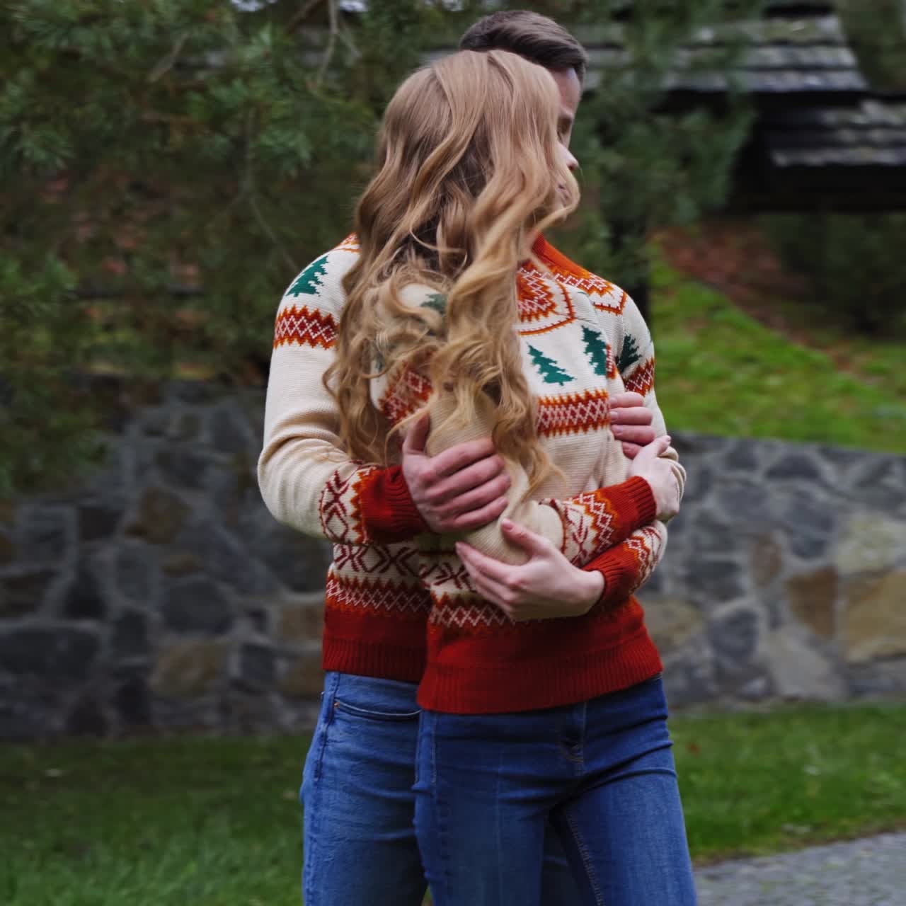 Lovely couple outdoors. Romantic couple in warm sweaters enjoying spending time together. Young man hugging the beautiful girl. Camera moves in around.
