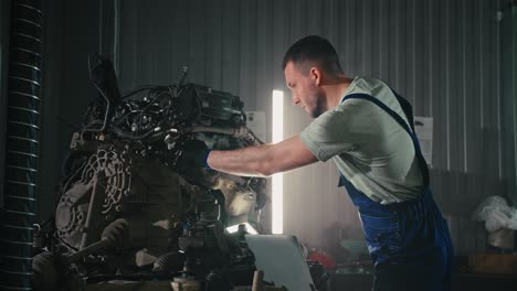 auto mechanic inspecting engine with laptop
